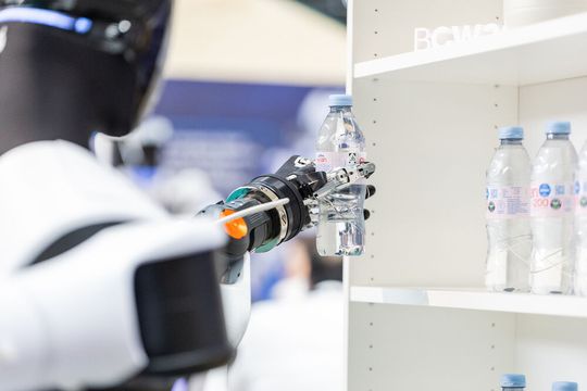 Ein humanoider Roboter entnimmt ein Getränk aus dem Regal und stellt es auf dem Tresen bereit. Die Demonstration auf der «Bosch Connected World 2026» zeigte zentrale Fähigkeiten humanoider Systeme in einem konkreten Handhabungsprozess.(Bild:  Schunk SE & Co. KG)
