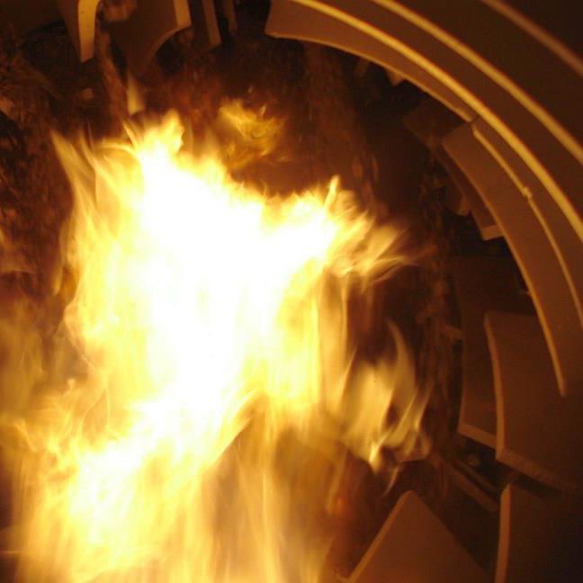 Blick in einen Trommeltrockner mit Flamme im Trommelinnenraum.