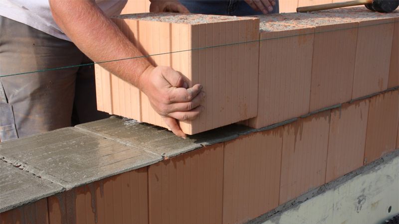 Gleichmäßig werden die Mauerziegel der Reihe nach auf die Mörtelpads gelegt. Mit einem Gummihammer werden sie im Anschluss eingearbeitet. (Bild:  maxit)