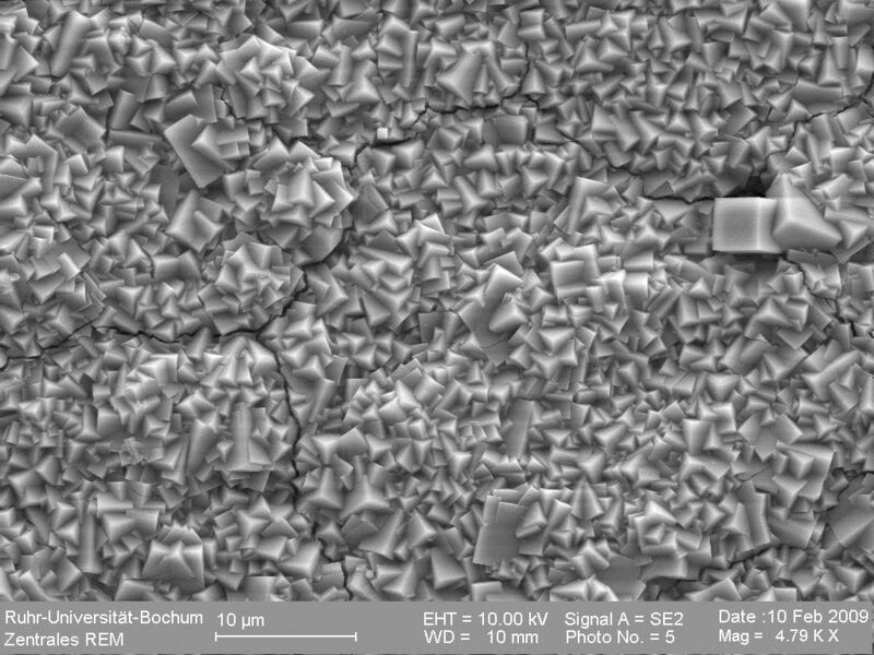 Elektronenmikroskopische Aufnahme einer Zeolith-Membran aus eng verwachsenen würfelförmigenSodalith-Kristallen. An mehreren Stellen sind Risse zu sehen, die durch thermische Ausdehnung entstanden sind. (Bild: RUB)