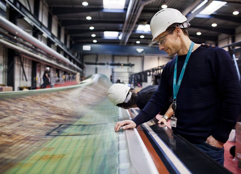 Bevor ein Rotorblatt die Fertigung verlässt, wird es genau auf mögliche Fehler und Risse überprüft. Nur so kann ein Rotorblatt den gigantischen Luftmassen standhalten: Wird der Rotor mit einem Durchmesser von 154 Metern bei einer Windgeschwindigkeit von zehn Metern pro Sekunde betrieben, fängt er pro Sekunde die Energie aus 200 Tonnen Luft ein. (Bild: Siemens)