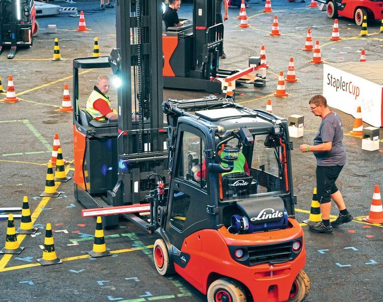 Im Parcours „Stange“ wurde zunächst eine Stange auf die Gabelzinken aufgenommen. Anschließend musste der zweite Fahrer im Team auf einem Schubmaststapler ein Gewicht auf der Stange platzieren… (© Klaus Voit / KION Group)