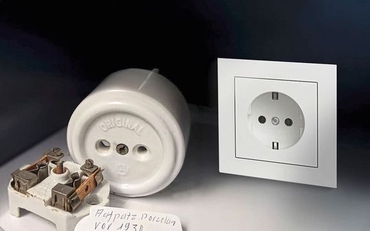 Mit der links zu sehen den Steckdose aus Porzellan fing bei Gira vor 100 Jahren eine produkttechnische Erfolgsgeschichte an, die sich bis heute fortsetzt, wie man rechts sieht.(Bild:  Gira)