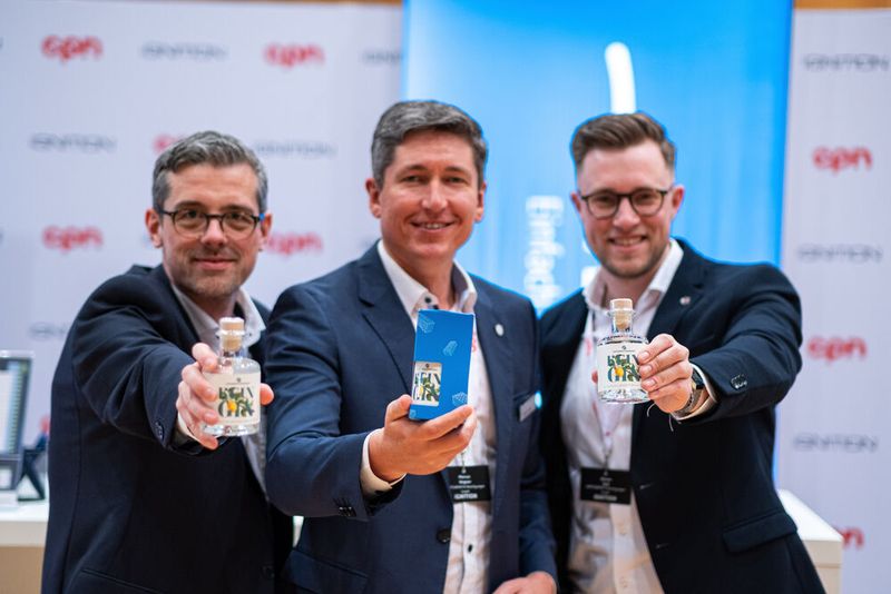 (V. l.) Stefan Baumann (Wertgarantie), Marcus Wagner (Wertgarantie) und Steven Golz (Wertgarantie) präsentieren ihr Werbegeschenk „Kein Gin“ aus geretteten Waffeln. (Bild: Niklas Christensen)