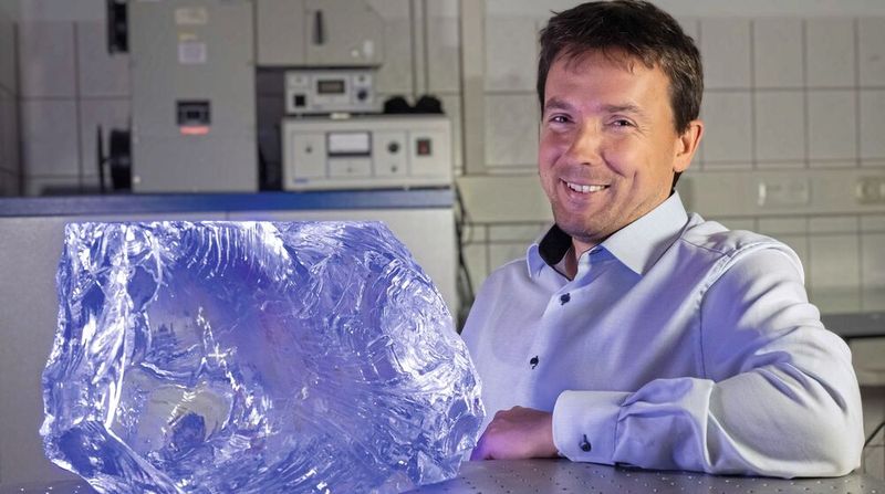 Prof. Lothar Wondraczek, Leiter des Otto-Schott-Instituts für Materialforschung, neben einem Glasblock bestehend aus hochreinem Borosilikatglas(Bild:  Jens Meyer (Universität Jena))