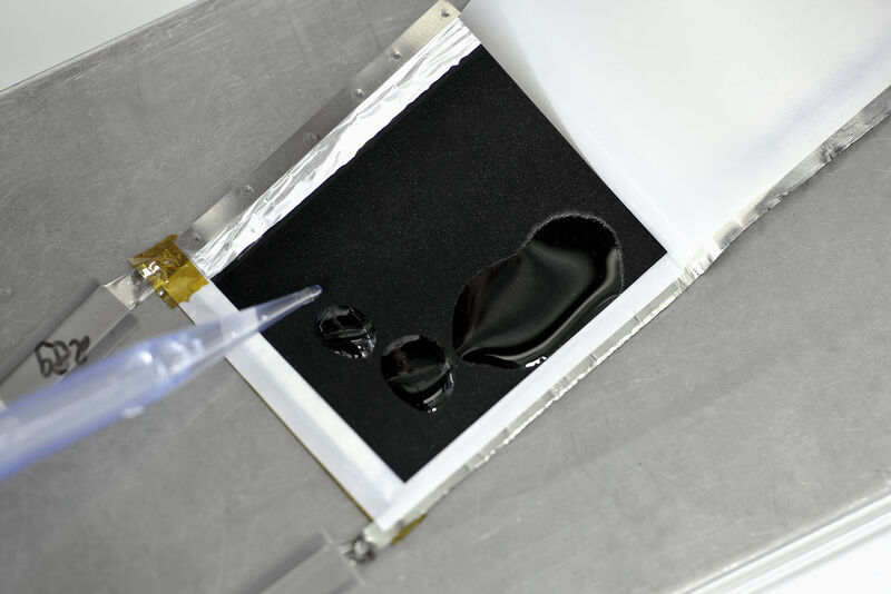Ein Chemielaborant tropft in einer Glove-box optimierte Elektrolyte auf die Kathode einer Lithium-Testbatterie. (Bild: BASF)