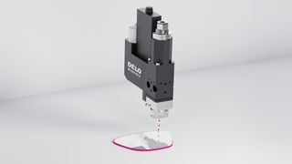 Jetventil Delo-Dot PN5 trägt die Kantenbeschichtung berührungslos und präzise auf eine AR-Glaskante auf; Beschichtung zur besseren Illustration in magenta dargestellt.  (Bild: Delo)