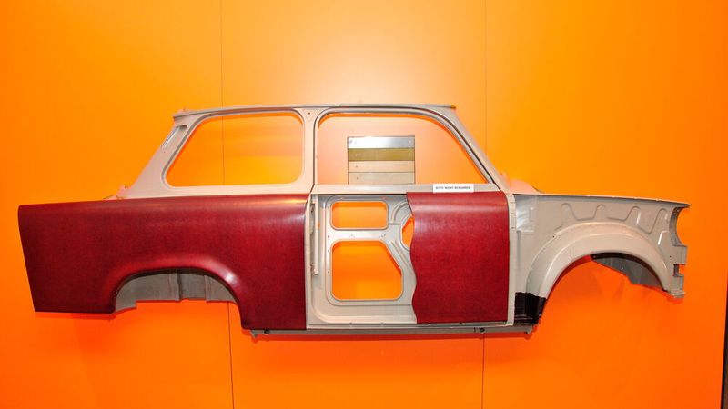 Eine Besonderheit des Trabants war das kunststoffbeplankte Stahlgerippe als Skelettkarosserie. Die Entwicklung des neuartigen Kunststoffs hatte 1951 begonnen, zunächst mit PVC, kombiniert mit Baumwollabfallfaser und Holzschliff. Eine günstige Lösung wurde in einem mit Baumwollkurzfasern verstärkten Phenolharz gefunden, das aus heimischer Braunkohle gewonnen wurde. Das Baumwollmaterial, das nicht zu spinnen und somit für die Textilherstellung ungeeignet war, sich jedoch zu Matten legen ließ, kam als Abfall aus der Sowjetunion. Diese Matten wurden auf einer Papiergrundlage in eine Form gelegt, mit Phenolharz getränkt und mit (um Luftblasen auszutreiben, mehrmals wiederholtem) Pressendruck bei circa 188 Grad Celsius geformt und ausgehärtet. (Bild: Dominsky – VCG)