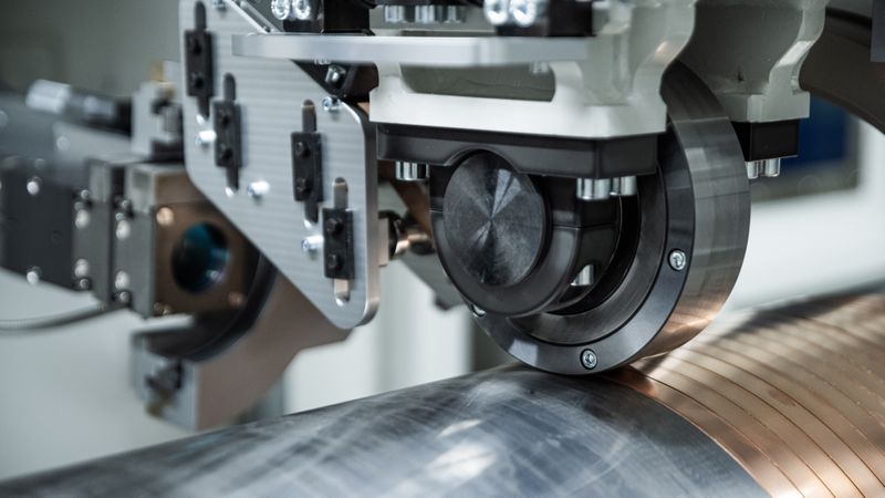 Das Fraunhofer IWS hat das neue Verfahren „Laserdirektplattieren“ entwickelt, das eine funktionale Schicht direkt auf dem Grundkörper erzeugt, indem ein bandförmiges Metall spiralförmig auf rotationssymmetrische Bauteile aufgebracht und lokal per Laser stoffschlüssig verbunden wird.(Bild:  Christoph Wilsnack/Fraunhofer IWS)