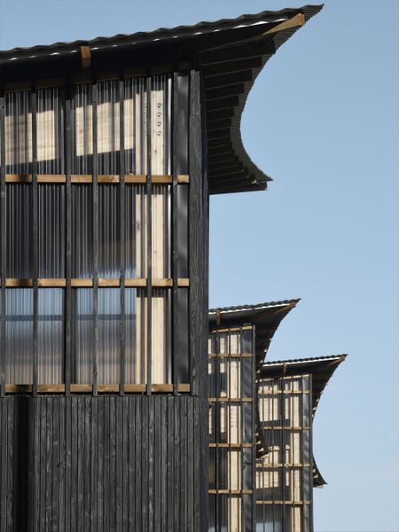 Die Fassaden bestehen aus verdunkelten Holzlatten, als ob sie in den Schatten des Vordachs eingetaucht wären.  (Bild: Guillaume Amat)