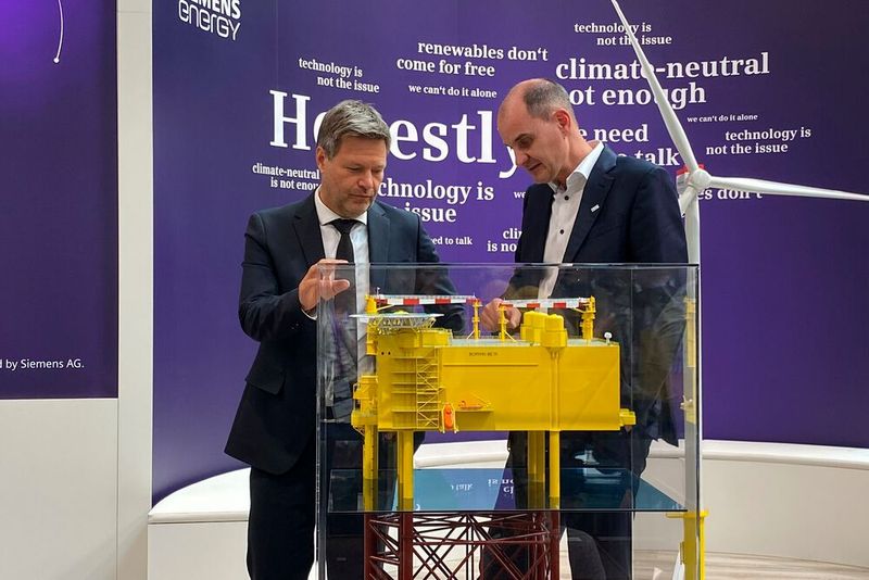 Robert Habeck und Tim Holt, Mitglied des Vorstands von Siemens Energy, begutachten auf der Hannover Messe das Modell einer Konverterplattform, die in der deutschen Nordsee dafür sorgt, dass Windenergie über weite Strecken an Land transportiert werden kann. (Bild: Siemens Energy)