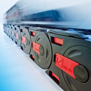 Es gleiten nicht mehr die Kettenseitenglieder - also Kettenober- und Kettenuntertrum – direkt aufeinander, sondern die Gleitschuhe.