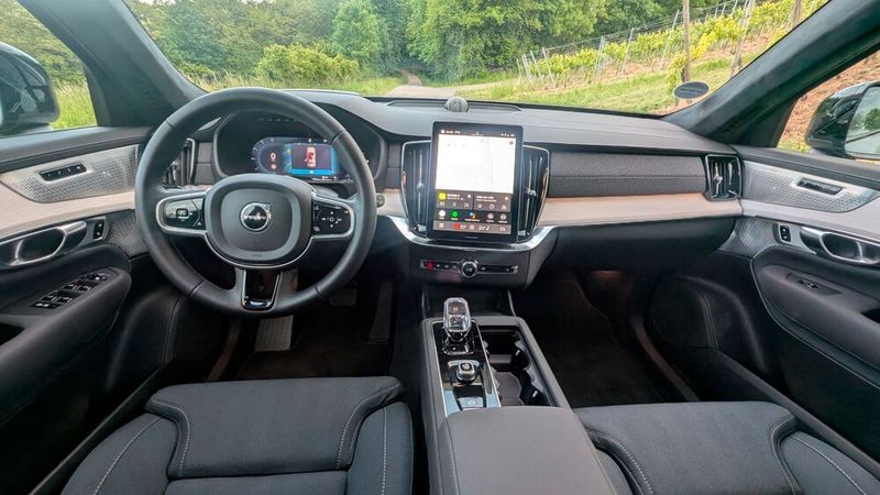 3. Der Innenraum: Das Raumgefühl im XC90 ist, wenig überraschend, sehr großzügig. Positiv zu erwähnen ist auch das klar fahrerorientierte Cockpit. Da Volvo auf klassische Tasten und Schalter verzichtet, kommen die Holzdekore und Stoffbezüge  zur Geltung. Den Innenraumdesignern ist es gelungen, eine skandinavische Hygge-Atmosphäre im SUV zu schaffen – und das ganz ohne Leder. Lediglich die Materialanmutung der Mittelkonsole und des unteren Cockpitbereichs ist etwas lieblos. (Bild: Mauritz – VCG)