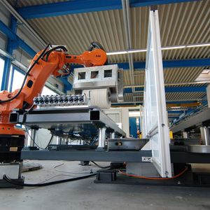 Mächtiger Aufbau für filigrane Werkstücke: Ein Schwerlastroboter führt ein Polieraggregat über mehrere Autozierleisten. Danach wird der Werkstückträger von einem WEISS CR700 Schwerlast-Rundschalttisch ausgetauscht.