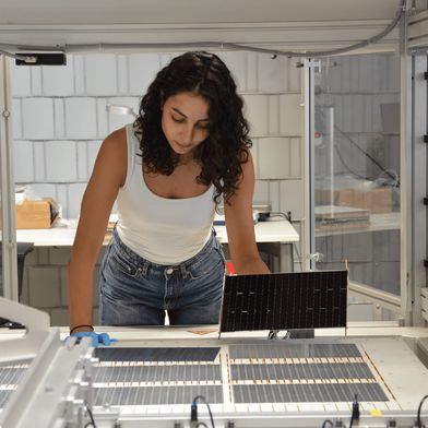 Die Projektleiterin am Fraunhofer ISE, Najwa Abdel Latif kontrolliert die verschalteten Solarzellen am Schindel-Matrix-Stringer des Fraunhofer ISE. (Bild: Fraunhofer ISE / Sophia Bächle)