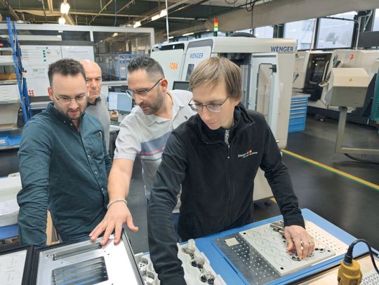 Mecid Birinci (Leiter Finishing, Diener AG) erklärt den Aufbau der unterschiedlichen Trays zur Aufnahme der Werkstücke.(Bild:  Teltec Systems AG)