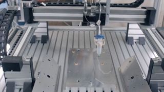 Raumportalroboter von Igus: Über drei Linearachsen trägt eine Kartusche Klebstoff auf die Seitenteile einer Edelstahlwanne des Tapeziergeräts auf.  (Bild: tapo-fix GmbH & Co. KG)