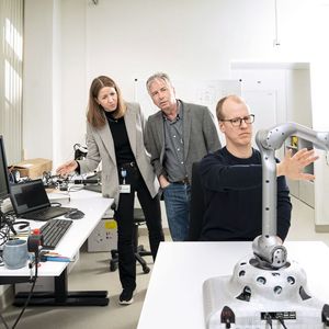 Prof. Dr. Yulia Sandamirskaya et Andreas Leu en arrière plan, tandis que Paul Fox, membre de l'équipe, présente le mouvement interactif du bras robotique avec la caméra 3D (intégrée en bas).(Source : Thomas Entzeroth)