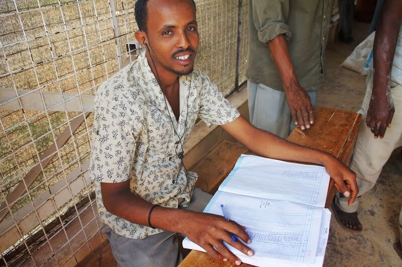 Der erste Mitarbeiter, der am Eingang der Ausgabestelle sitzt, prüft dir Rationskarten und familiengrößen auf übereinstimmung mit dem UNHCR Manifest. Wenn die Hilfesuchenden korrekt registriert sind, dürfen sie eintreten und ihre Rationen in Empfang nehmen. (Photo: 2013 CARE Kenya / Mary Muia)