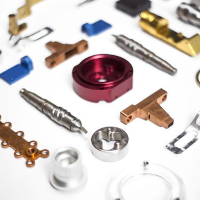 Detailansicht verschiedener Bauteile, darunter rot eloxiertes Aluminium. Digitale Plattformen sichern hierbei die lückenlose Rückverfolgbarkeit bis zum Rohmaterial. (Quelle: FACTUREE - Der Online-Fertiger)