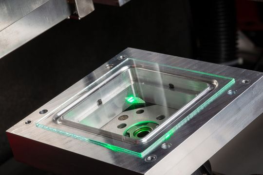 Besser als mit Flusssäure drangehen! Per UKP-Laser wird hier ein Glasrohling mit Pikosekundenpulsen bearbeitet, damit er Mikro- oder Nanostrukturen bekommt. Das klappt präzise, aber vor allem umweltschonender als mit den üblichen Methoden. Doch da gibt es noch mehr ...(Bild:  Fraunhofer IPT)