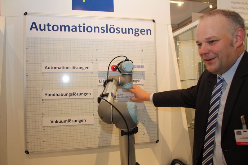 Lothar Vandeberg von Müller Maschinentechnik zeigt wie ein Roboterarm durch Berührung gestoppt wird. Deswegen darf er ohne gesonderte Sicherheitsvorkehrungen mit dem Menschen zusammen arbeiten. (Finus)