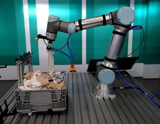 Hier wühlt der Roboter in der Wäschetruhe! Was irgendwie lustig aussieht, hat einen nüchternen Hintergrund – Das Sortieren von Altkleiderhaufen ist bisher kaum automatisierbar gewesen. Doch das wollen Forscher vom IPA aus Stuttgart mit dem Partner Polysecure nun ändern ...(Bild:  Fraunhofer IPA)
