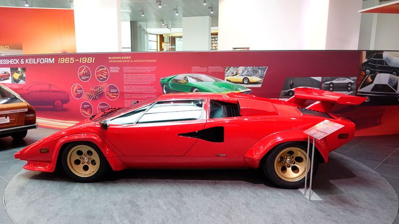 Die Karosserie des Countach ist ein Entwurf des Bertone-Designers Marcello Gandini. Der Vorderwagen geht annähernd stufenlos in die stark geneigte Windschutzscheibe über, die ihrerseits eine Linie mit der flach auslaufende Dachpartie bildet. Das rundlich verlaufende Profil kontrastiert mit Ecken und Winkeln an den Fahrzeugflanken und am Heck. Sogenannte NACA-Lufteinlässe in den Flanken und große Lufthutzen auf den hinteren Kotflügeln verleihen dem Wagen ein spektakuläres Aussehen, verschlechtern aber massiv die Aerodynamik, sodass der Countach nur auf einen cW-Wert von circa 0,42 kommt. (Bild: Dominsky – VCG)
