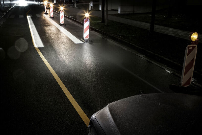 In engen Baustellendurchfahrten beispielsweise wird der Fahrer gezielt per Lichtschiene geführt. Dazu wird eine Lichtspur auf die Straße projiziert, die dem Fahrer die Fahrzeugbreite anzeigt und ihn sicher leitet. Aktiv oberhalb von 30 km/h.  (Daimler AG)