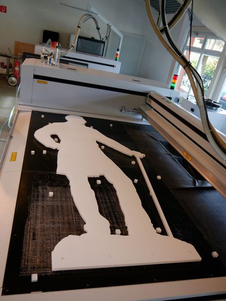 Mann mit Stock: Eine der lebensgroßen Museums-Figuren auf dem Bearbeitungstisch einer Eurolaser-Anlage. Noch mit Schutzfolie beklebt. Man beachte die große Bearbeitungsfläche. (Bild: Eurolaser)