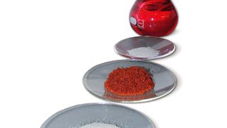 Das Bild zeigt von vorn nach hinten den Scavenger vor der Beladung mit Edelmetall, die rot-orange Probe des mit Rhodium beladenen Scavengers, die Reste des edelmetallfreien Scavengers, nachdem das Edelmetall im Recyclingprozess wieder abgelöst wurde sowie die rhodiumhaltige Lösung, aus der sich das Metall wieder gewinnen lässt.  (Bild: Heraeus)