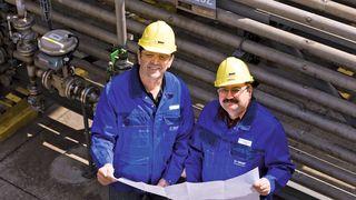 Den Plan für die Umbauten in der Hand: A. Kaceri (links) und W. Meyer vor einem Wasserkühler in der Hydraminfabrik in G 500.  (Bild: H.-J. Doelger, BASF)
