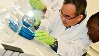 Shih Mean Lee (NMC, Singapur) und Wilson Ombati (KEBS, Kenia) überprüfen, ob sich Staubpartikel auf der Si-Kugel befinden.  (Bild: PTB )