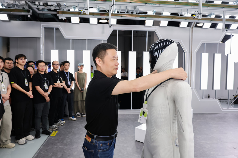 He Xiaopeng hangs an employee ID badge around the neck of the humanoid "IRON," as part of the team.(Source:  Xpeng)