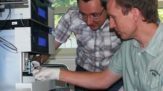 Abb. 1: Andreas Schrötter (links) und Dr. Thorsten Müller setzen die Probe ins Massenspektrometer ein, mit dem sie die Proteinausstattung von Zellen analysieren. (Bild: Christina Looße)