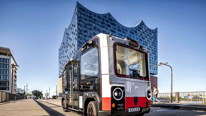 Hamburg setzt einen weiteren Meilenstein auf dem Weg zum autonomen ÖPNV: Der erste autonome Holon urban ist in der Hansestadt angekommen. Der fünf Meter lange Kleinbus ist barrierefrei, bietet Platz für bis zu 15 Fahrgäste und kann bis zu 60 km/h fahren. Die ersten Fahrgäste werden ab 2026 zusteigen können.(Bild:  Holon & Benteler)