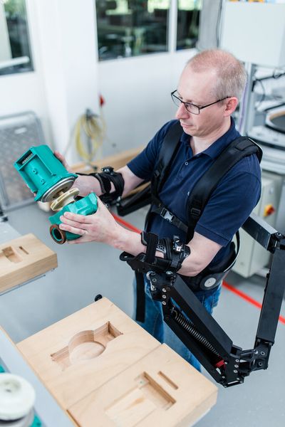 Dr. Konrad Stadler, Dozent für Regelungstechnik, Zürcher Hochschule für Angewandte Wissenschaften, demonstriert die Funktionsweise des Exoskeletts. Zu sehen ist die passive Unterstützung zum Heben schwerer Lasten. (Bild: Ludmilla Parsyak/Fraunhofer IAO)