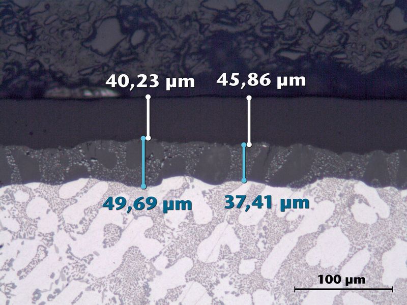 Bild 2: Auf dem Aluminiumguss (hell) befindet sich Harteloxal als Basis- und PFA als Deckschicht. Die Porenstruktur von Harteloxal bietet einen guten Haftgrund für PFA (Schliffbild). (Bild: AHC)