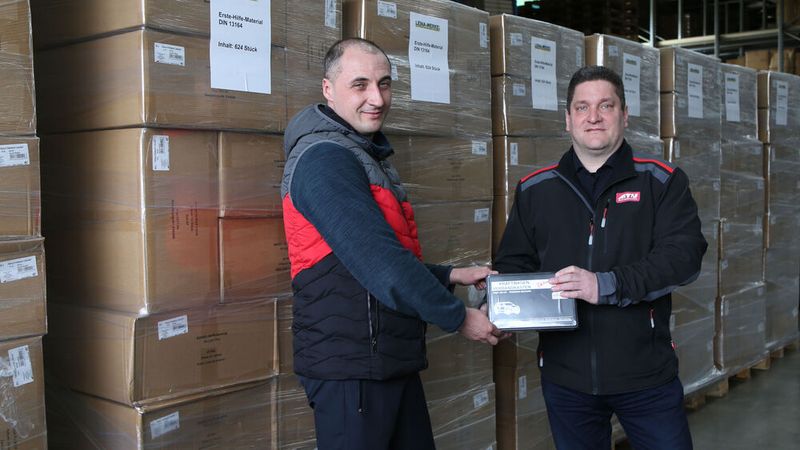 ATU Werkstattleiter Volker Müller (rechts) übergibt die 50.000 Verbandspäckchen an den Fahrer eines Logistikpartners der Johanniter.  (Bild: ATU)