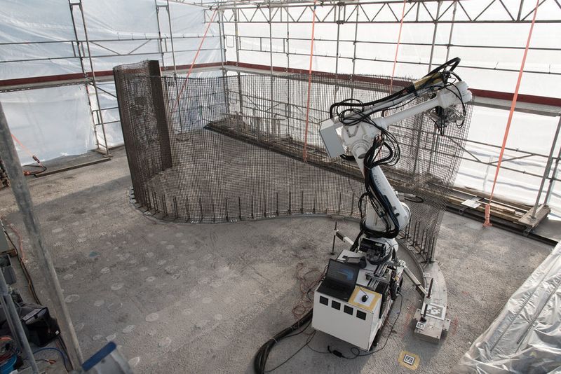 Der Bauroboter „In situ Fabricator“ baut mithilfe der „Mesh Mould“-Technologie ein Stahldrahtgitter im Forschungsgebäude. Die Technologie kombiniert die beiden Funktionen Schalung und Bewehrung des Betons in einem Stahldrahtgitter. Die Fertigung einer Wand geschieht in einem einzigen von Robotern kontrollierten Prozess. (NCCR Digital Fabrication, 2017)