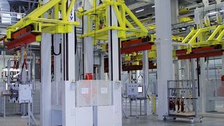 Bild 1: Drei Be- und Entlademanipulatoren übernehmen die Transporttraversen (rot), in die bis zu 3,5 t schwere Großgetriebe gehängt werden. Reibräder statt Schleppketten sorgen für Vorschub. Bild: Vollert (Archiv: Vogel Business Media)