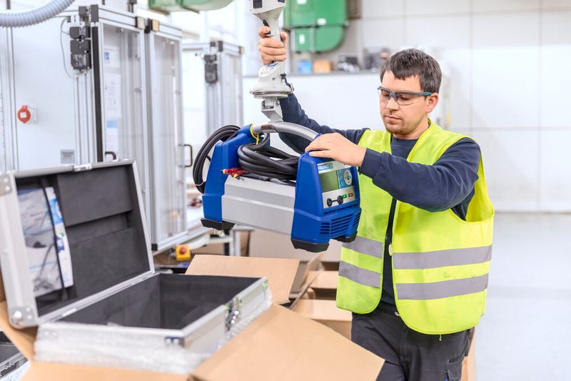 Der Handgriff des Friamat-Schweißgerätes passt sehr an den Haken des Jumboflex-Schlauchhebers, wie man hier sieht. So hebt der Werker das Gerät in die Prüfstation und anschließend in den Koffer. (Bild: M. Wagenhan)