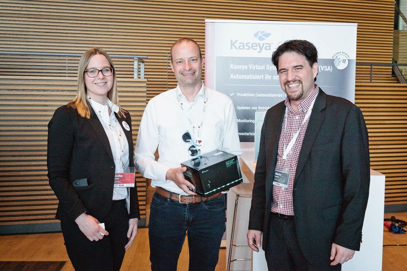 v. l.: Freude bei Oliver Heer (NIC Systemhaus) über den Gewinn aus der Verlosung von Kaseya mit der Glücksfee Anika Bode (Synaxon) und dem Sponsor Martin Lambert (Kaseya)  (Synaxon)
