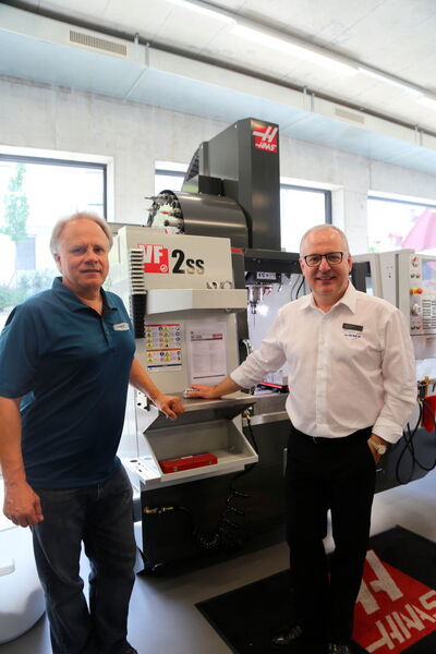 Gene Haas directeur général de Haas Automation Inc, et Urs W. Berner directeur d'Urma AG le distributeurs des machines-outils Haas en Suisse (de gauche à droite). En arrière plan le centre d'usinage Haas VF-2SS Super-Speed 762x406x508 mm, 22,4 kW et 12'000 tr/min. (JR Gonthier)