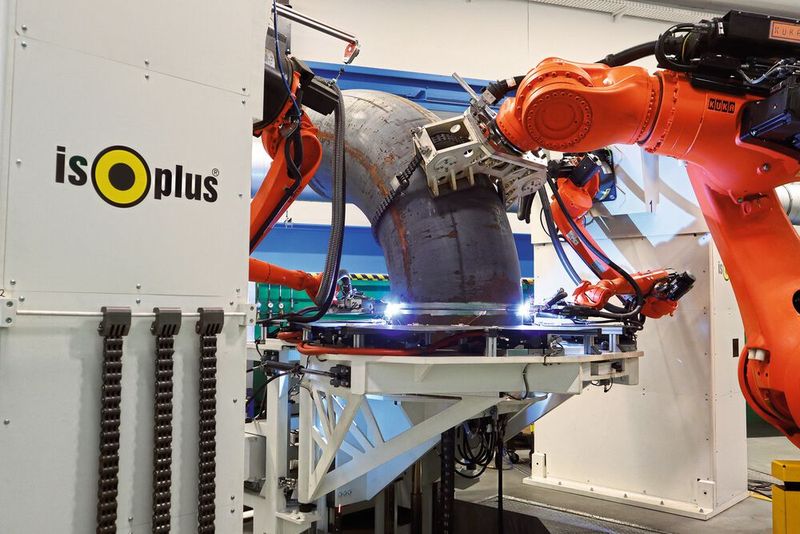 Der große Kuka-Handlingroboter hebt den Rohrbogen millimetergenau in Position über das eingespannte  Rohrende und hält ihn zuverlässig während des gesamten  Fertigungsprozesses. (Bild: Isoplus)