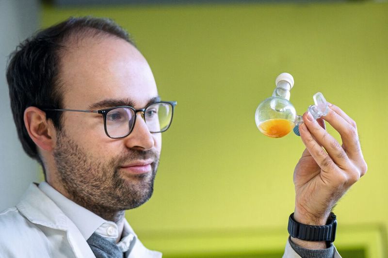 Dr. Philip Stanley kontrolliert einen Kolben, in dem sich das neue Material in einer wässrigen Lösung befindet (Bild: Astrid Eckert – TUM)