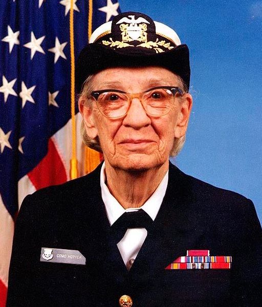 Grace Hopper entwickelte 1952 den ersten Compiler (A-0 System), der mathematischen Code in maschinenlesbaren Code übersetzte und damit die Grundlage für die moderne Programmierung schuf. Sie war maßgeblich an der Entwicklung der Programmiersprache COBOL beteiligt, die es ermöglichte, Computer mit englischen Wörtern statt mathematischen Symbolen zu programmieren und dadurch die IT für Menschen ohne technischen Hintergrund zugänglich machte. (Bild: Commodore Grace M. Hopper, USNR Official portrait photograph. Gemeinfrei.)