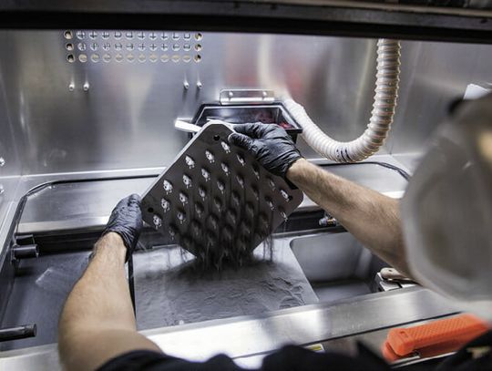 (Experte entnimmt lasergesinterte Bauteile nach dem Druckvorgang. Bild: Protolabs)