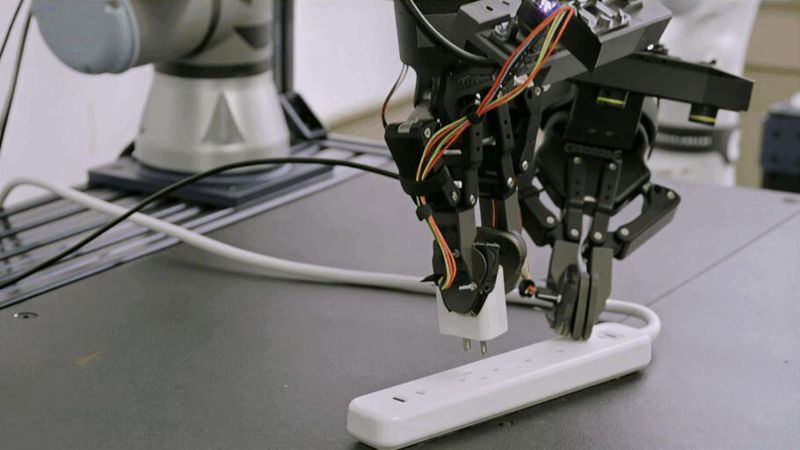 Ein Roboter greift einen Stecker und passt seine Bewegung situativ an: Rho-alpha dient Microsoft Research als Forschungsplattform, um zu zeigen, wie Simulation und synthetische Trainingsdaten das Lernen physischer KI skalierbar machen sollen.(Bild:  Microsoft)