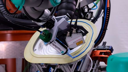This is a new development from Fraunhofer IFAM and partners: an automated adhesive splitting system for the reliable and more productive bonding of composite parts. Here, a frame for an airplane window is measured in real time and a precise amount of adhesive is applied.(Image: Fraunhofer IFAM)